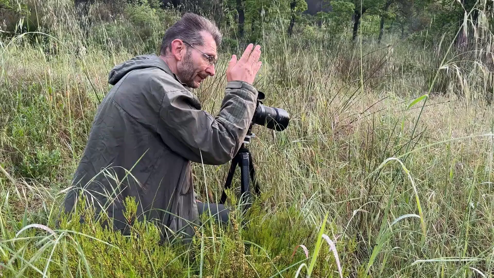 Photographe installé à hauteur d’herbe avec son boîtier